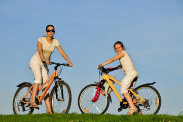 Fototapeta premium Mother and her dauhgter riding on a bicycles