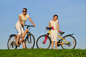 Mother and her dauhgter riding on a bicycles