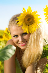 The beautiful smiling girl in the field with sunflowers