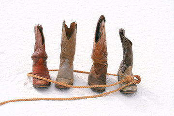 Old roped cowboy boot on sand dune