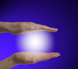 hands and healing light on blue background