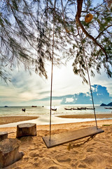 Swing on a tropical beach against the setting sun