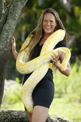 Fototapeta premium Young woman plays with an albino burmese python