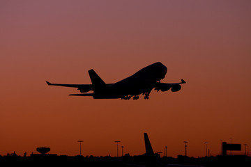 Silhouette of jet in flight at sunset.