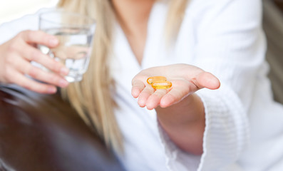Jolly woman  holding pills and a glass of water smiling
