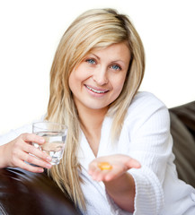 Obraz na płótnie Canvas Happy woman holding pills and a glass of water smiling