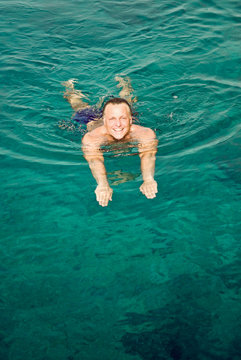 happy smiling man swimming in beautiful turquoise sea.