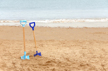 Fototapeta na wymiar Two children's spades on a sandy beach
