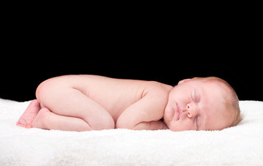 Newborn sleeping child on white blanket
