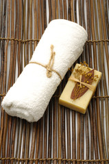 Fototapeta na wymiar White towel and nature soap on bamboo mat