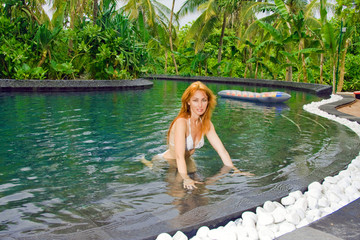 Fototapeta premium Young pretty woman in pool in tropical garden..