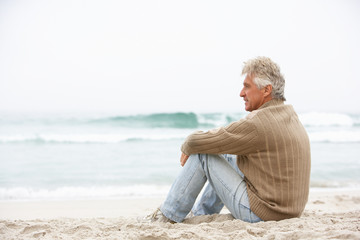 Fototapeta na wymiar Senior Man On Holiday Sitting On Winter Beach