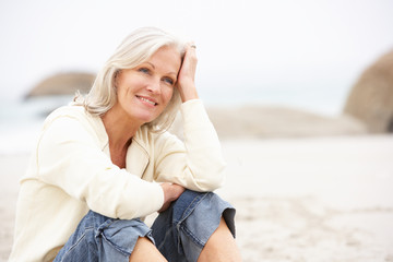 Senior Woman On Holiday Sitting On Winter Beach
