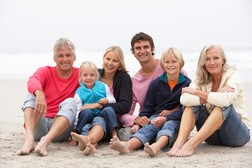 Three Generation Family Sitting On Winter Beach Together