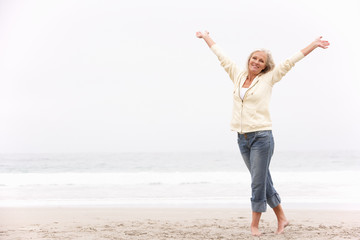 Senior Woman With Arms Outstretched On Winter Beach