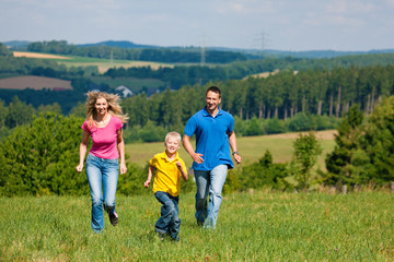 Family running on meadow in summer