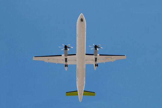 unmarked propeller aircraft overhead with landing gear down