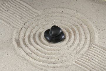 Fototapeta na wymiar Czarne Kamienie gorącymi kamieniami w piasku ślady