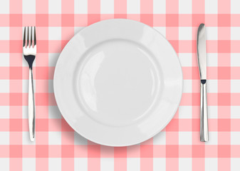 Knife, white plate and fork on blue checked tablecloth