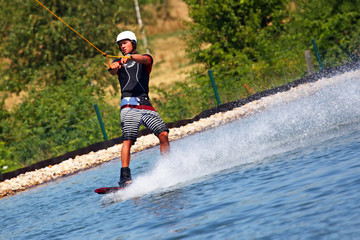 Junger Mann Wakeboarder rast über das Wasser