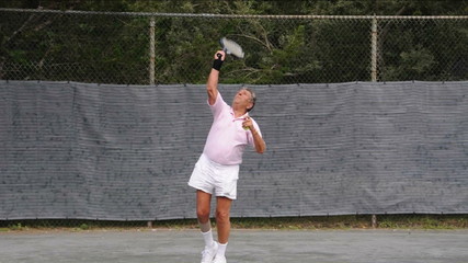 handsome senior male tennis player practicing tennis serve