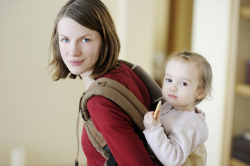 Young mother and her girl in a baby carrier