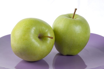 Fresh green apples on the purple plate