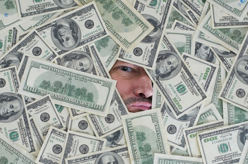 man looking through a hole between dollar bills
