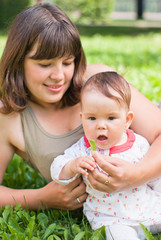 happy mom with a little girl resting on the grass in the park