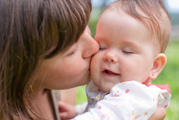 Mom kisses her little daughter, played in the park