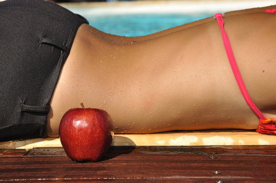 Femme allongée au bord de la piscine avec une pomme