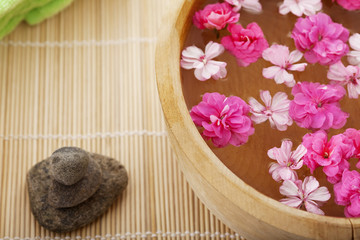 Fototapeta na wymiar Spa therapy, flowers in water, on a bamboo mat.