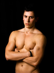 Fototapeta premium Young man with atletic body on black background