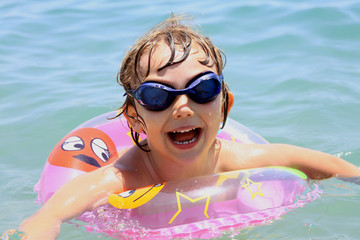 little girl with glasses swims in the sea - obrazy, fototapety, plakaty