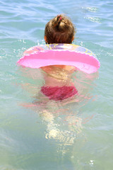 Girl swims in the sea in the pink circle - obrazy, fototapety, plakaty
