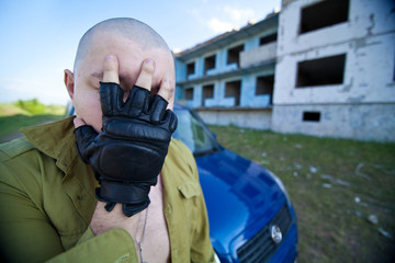 Portrait of a skinhead man near ruined building.