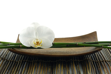 Wooden bowl of orchid and bamboo on mat