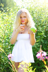 Beautiful girl is holding an apple and juice