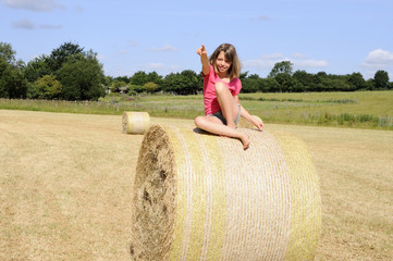 Naklejka na ściany i meble one girl showing from hay bales in summer season
