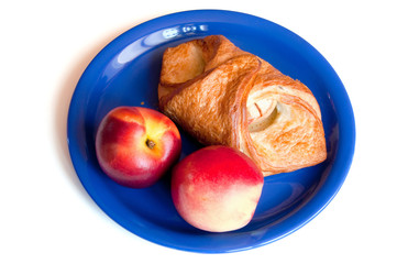 croissant and red peaches on the blue plate