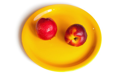 Two red peach on a yellow plate