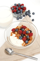 Serving of yogurt with fresh berries, muesli and milk on white b