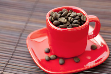 cup and saucer and coffee beans on a bamboo mat