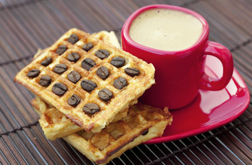 cup of cappuccino wafers and coffee beans on a bamboo mat