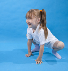 Small girl is posing as frog on blue