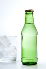 Bottle and glass of mineral water on white background