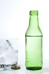 Bottle and glass of mineral water on white background