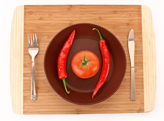 Plate with pepper, tomato, fork and knife isolated on white