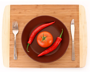 Plate with pepper, tomato, fork and knife isolated on white