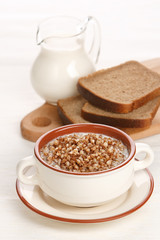 Boiled buckwheat with milk on served table on white background